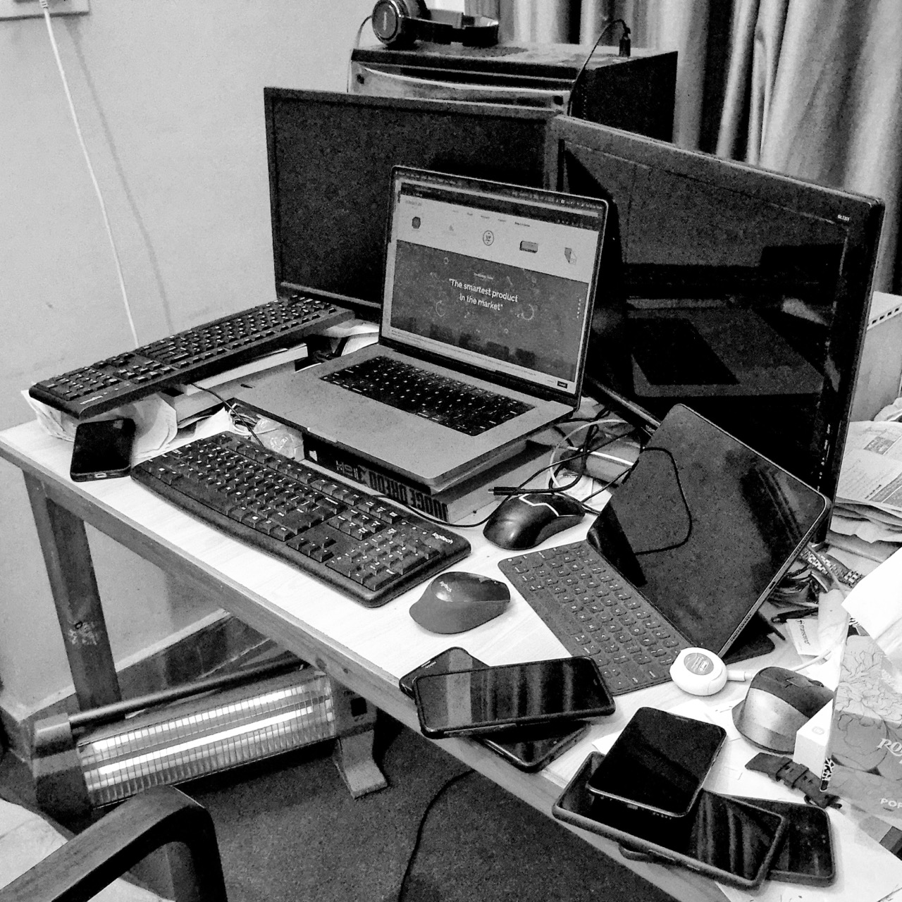 photo of my messy desk with a laptop, two 1080p displays, my desktop, too many phones, a first gen ppc macmini, and an electric heater.
